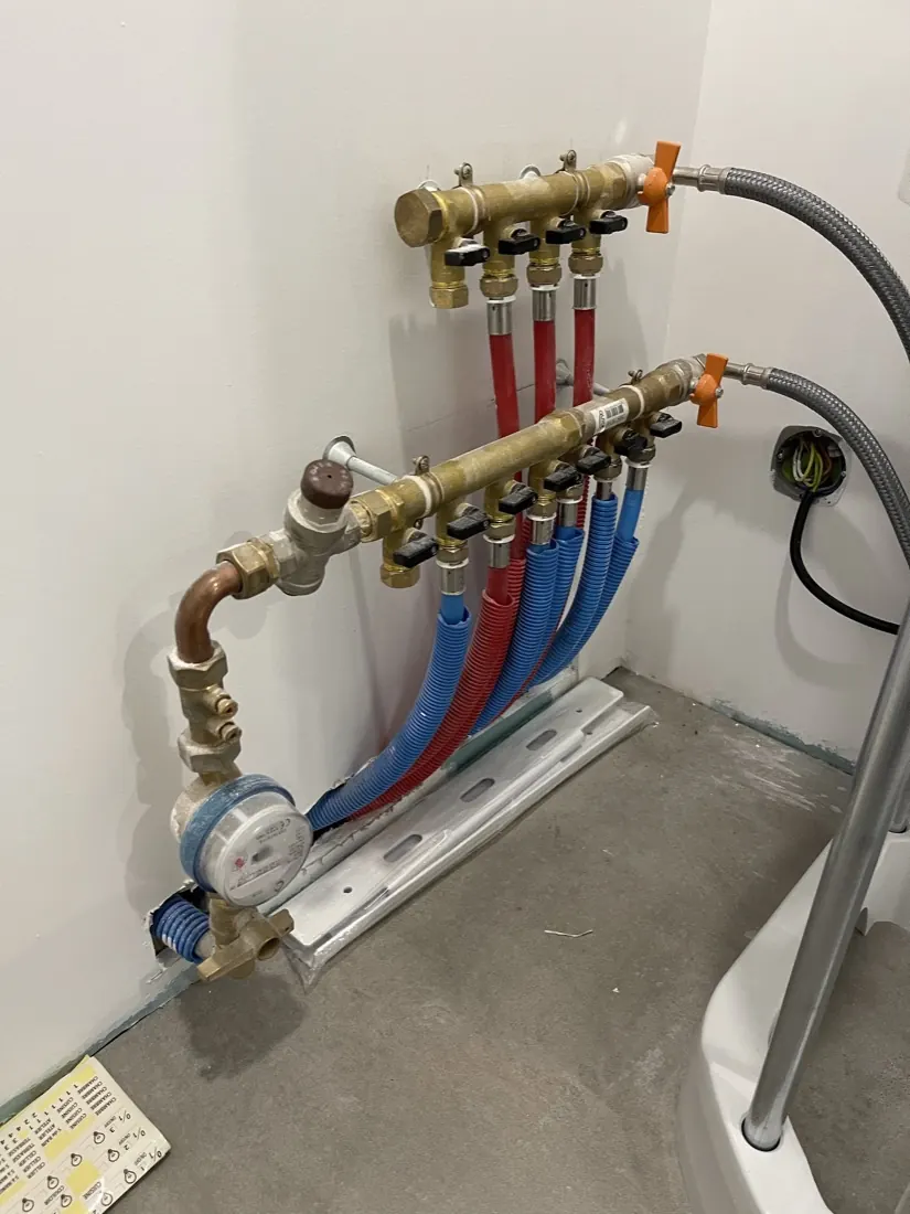 Collecteur en laiton avec tuyaux multicouche rouges et bleus et compteur d'eau